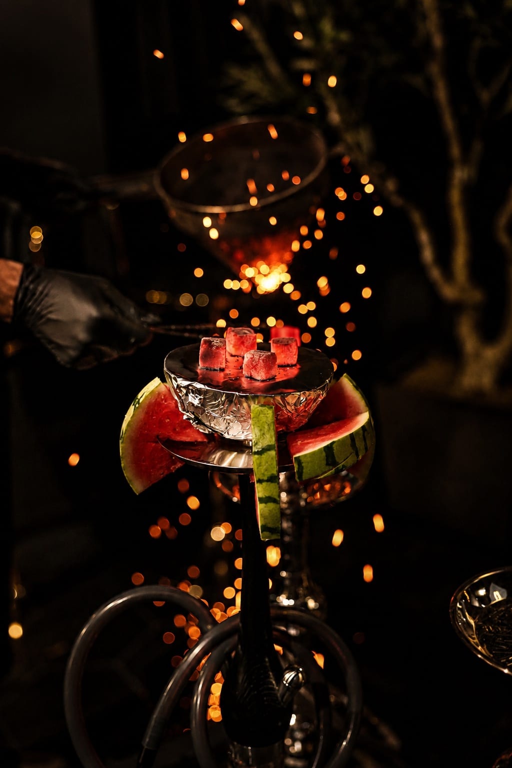 Watermelon hookah with glowing coals and rising embers